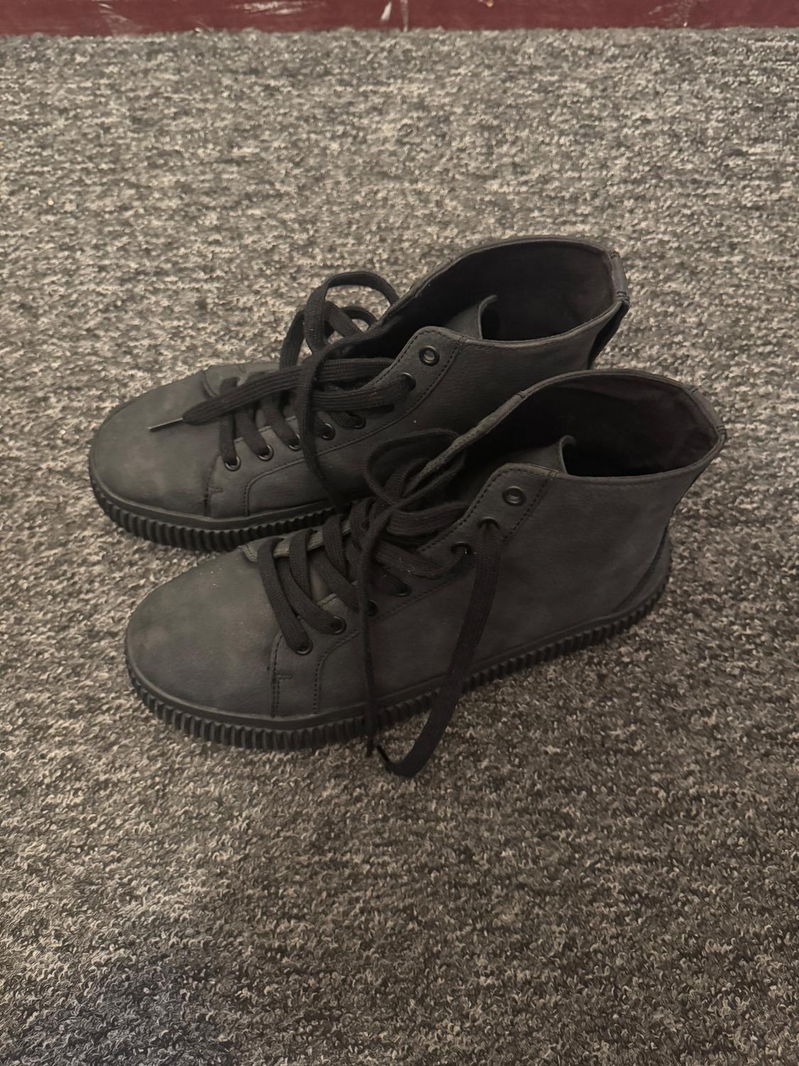 Black canvas lace-up boots on a grey rug. Casual and modern style, top view.
