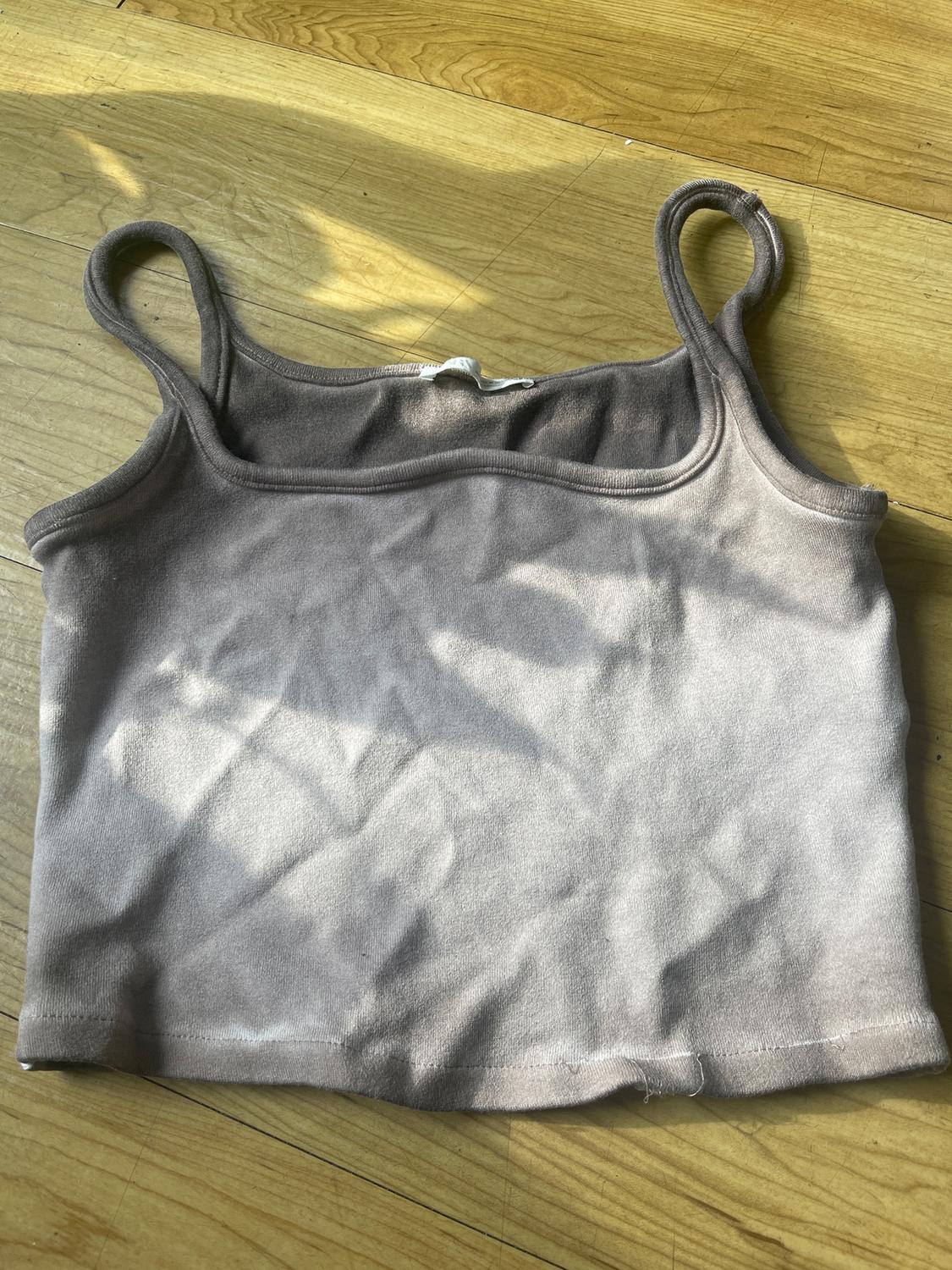 Gray crop top with thin straps on a light wood floor. The light creates soft shadows on the fabric.