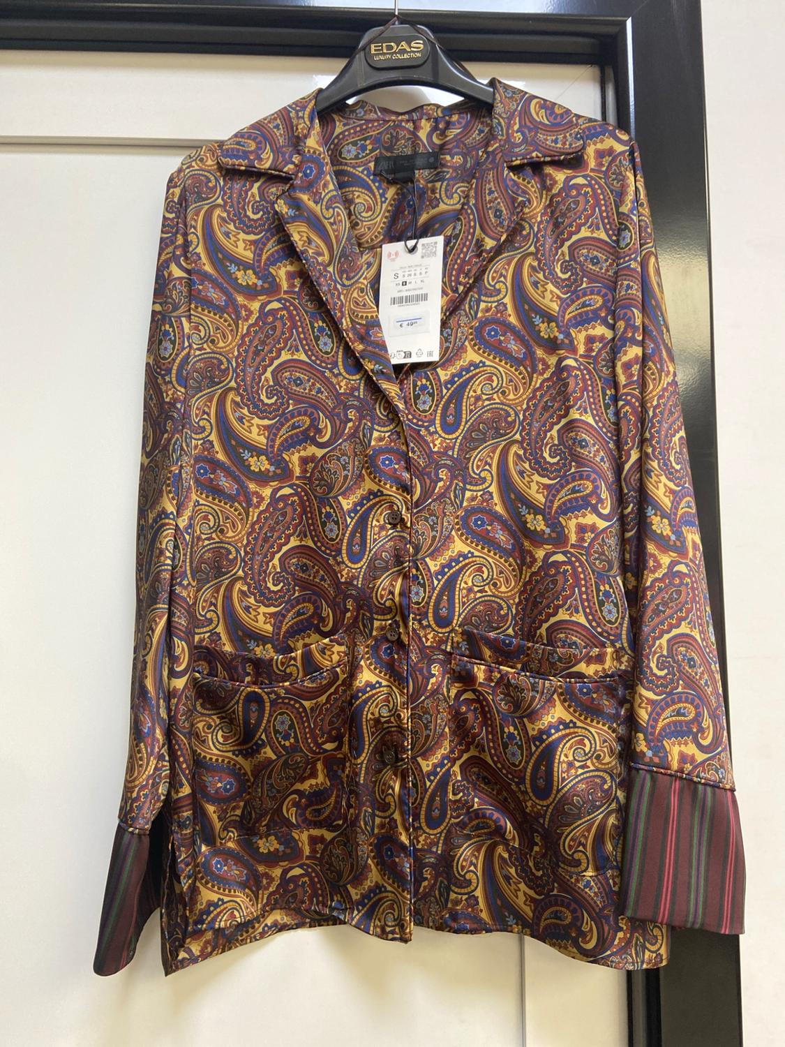 Long-sleeved shirt with a paisley print and striped cuffs, hanging on a hanger. Text: EDAS LUXURY COLLECTION.