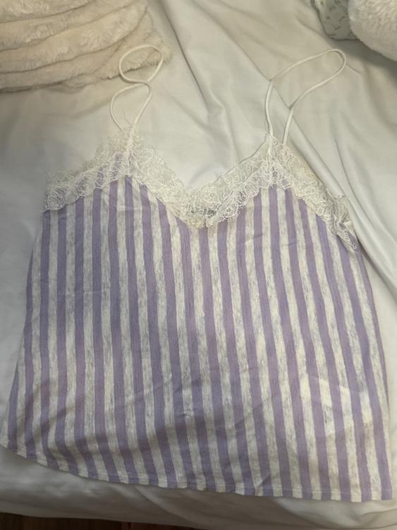 White lace tank top with lilac and white vertical stripes on a white bed with fluffy pillows.