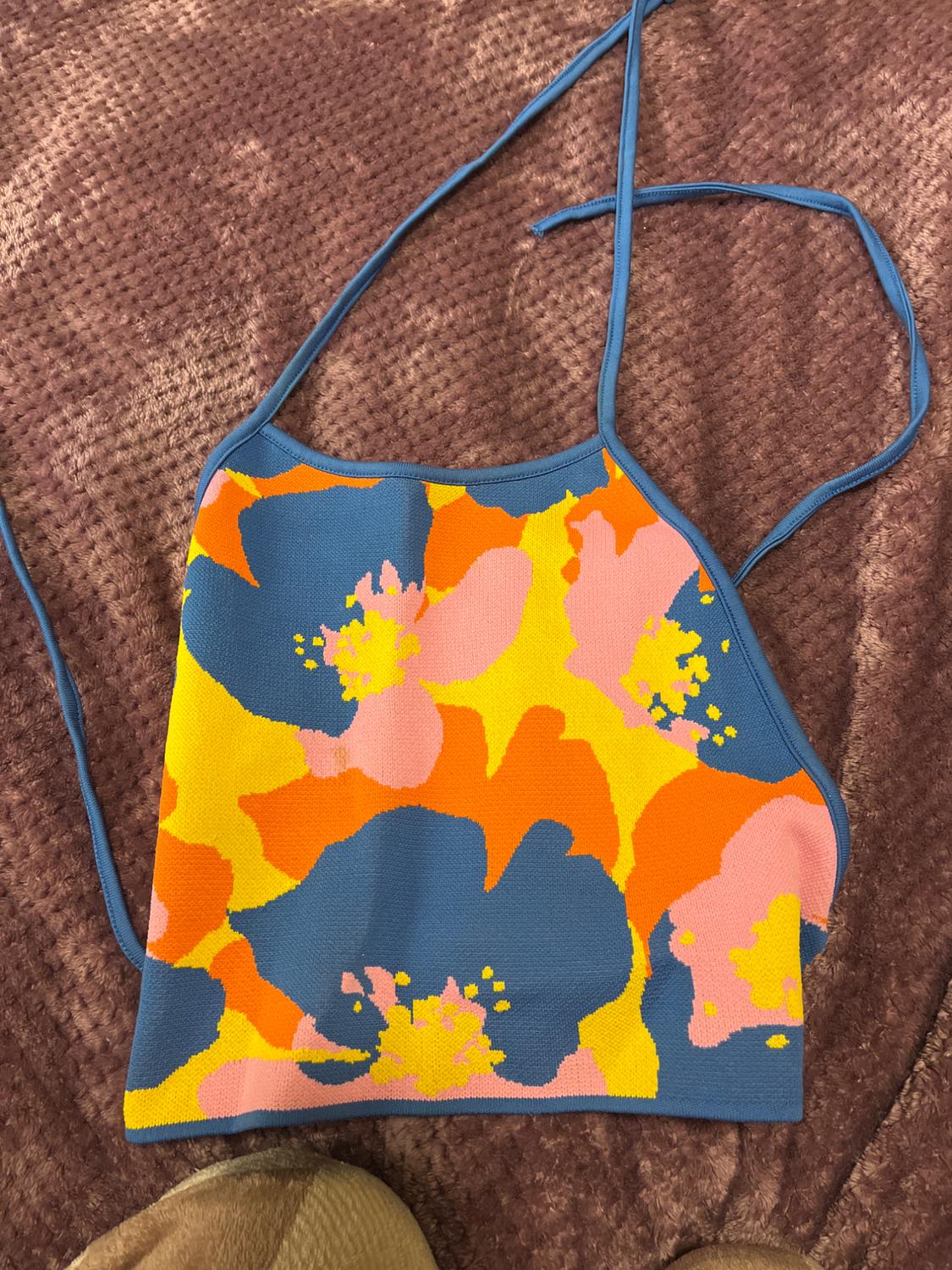 Floral print camisole top in blue, orange, pink, and yellow tones on a textured brown background.
