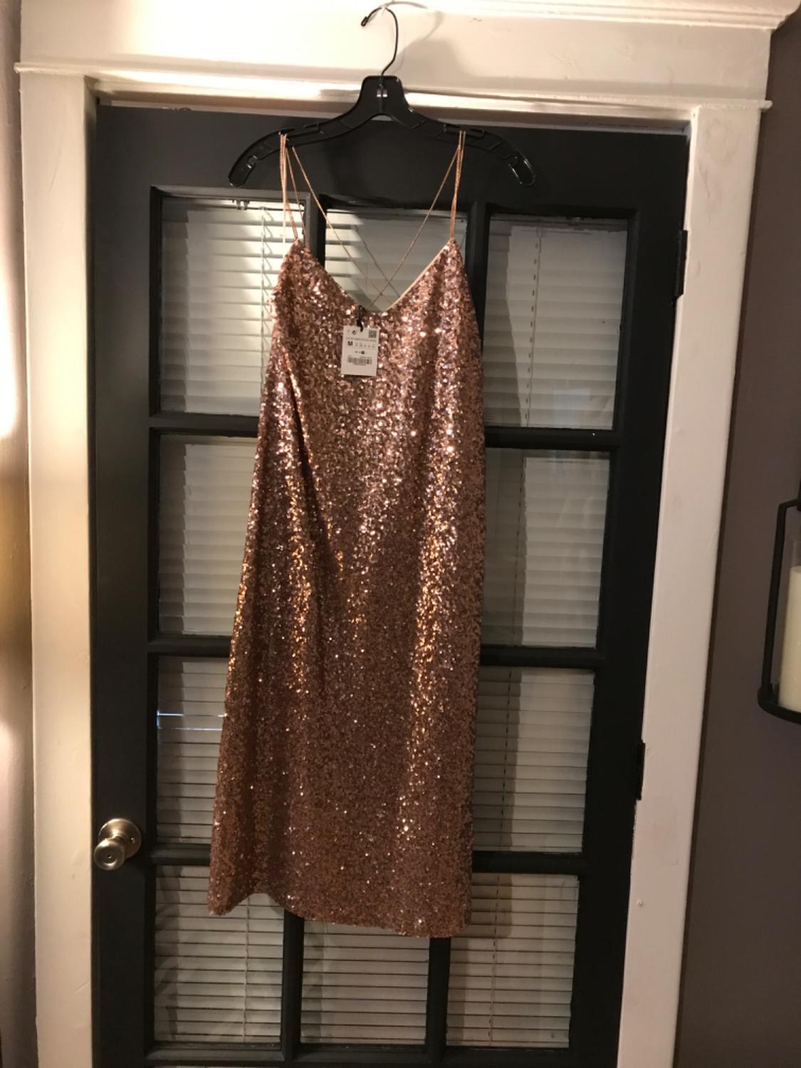 Front view of a gold sequined dress with thin straps and a visible label at the top.
