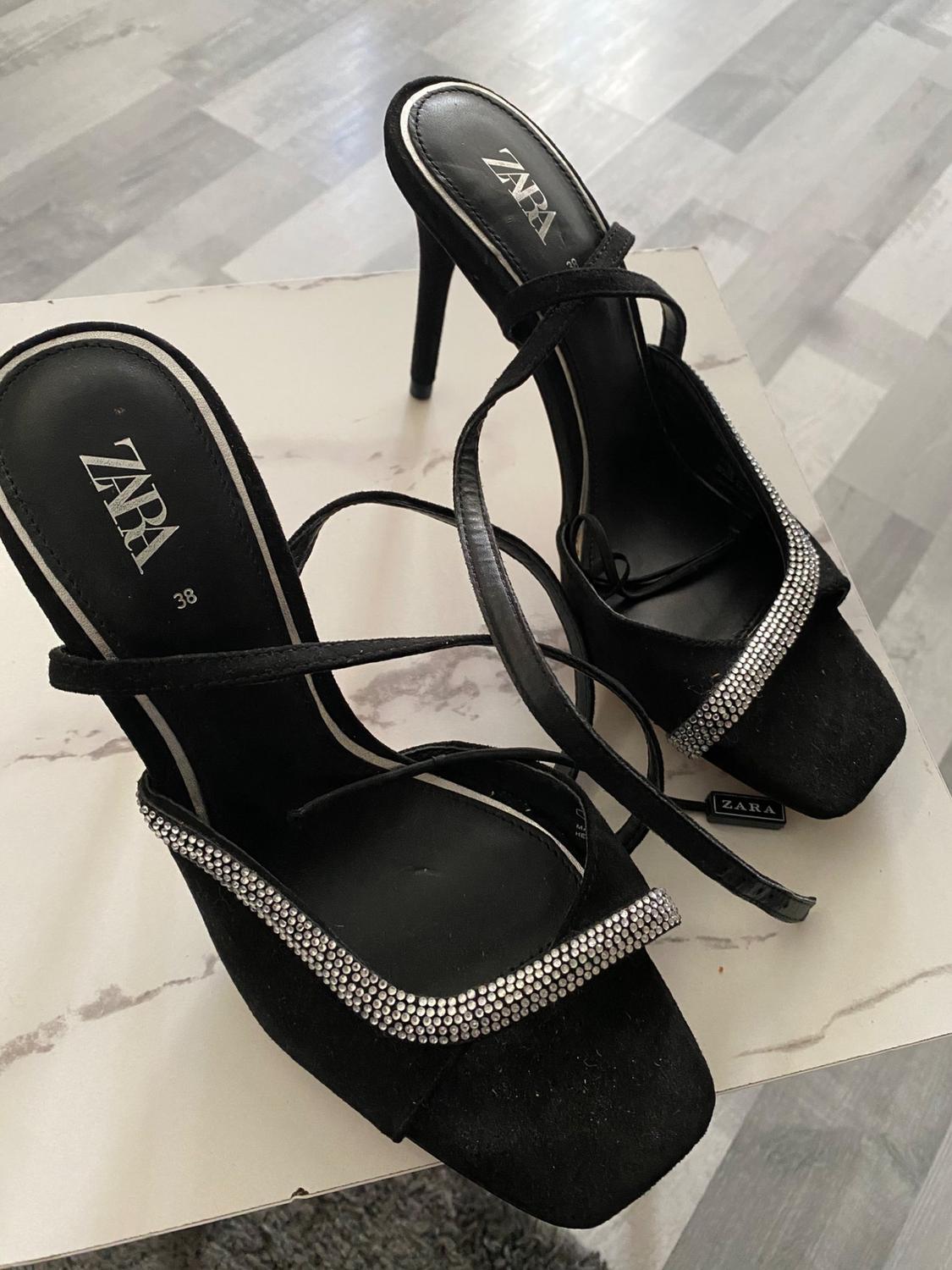 Detail of black strappy high-heeled sandals with sparkling embellishments.