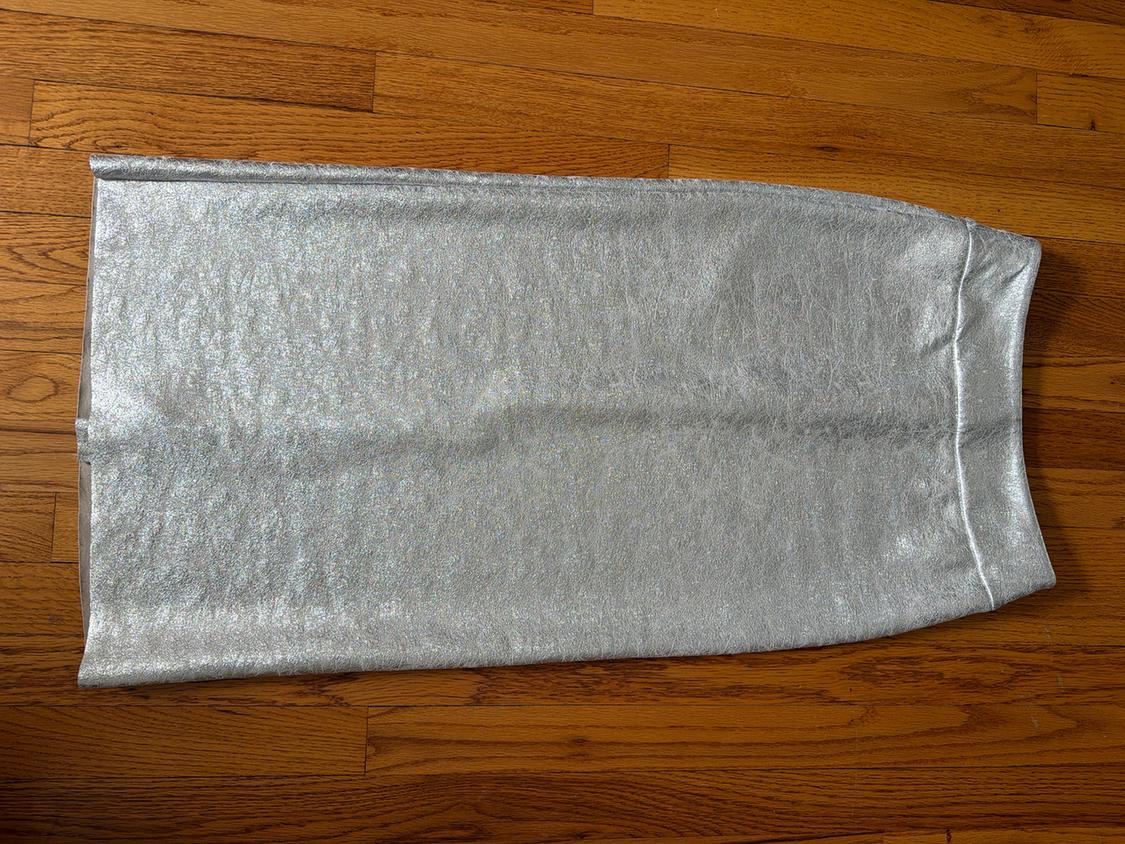 Long silver skirt with a shimmering texture on a wooden floor.