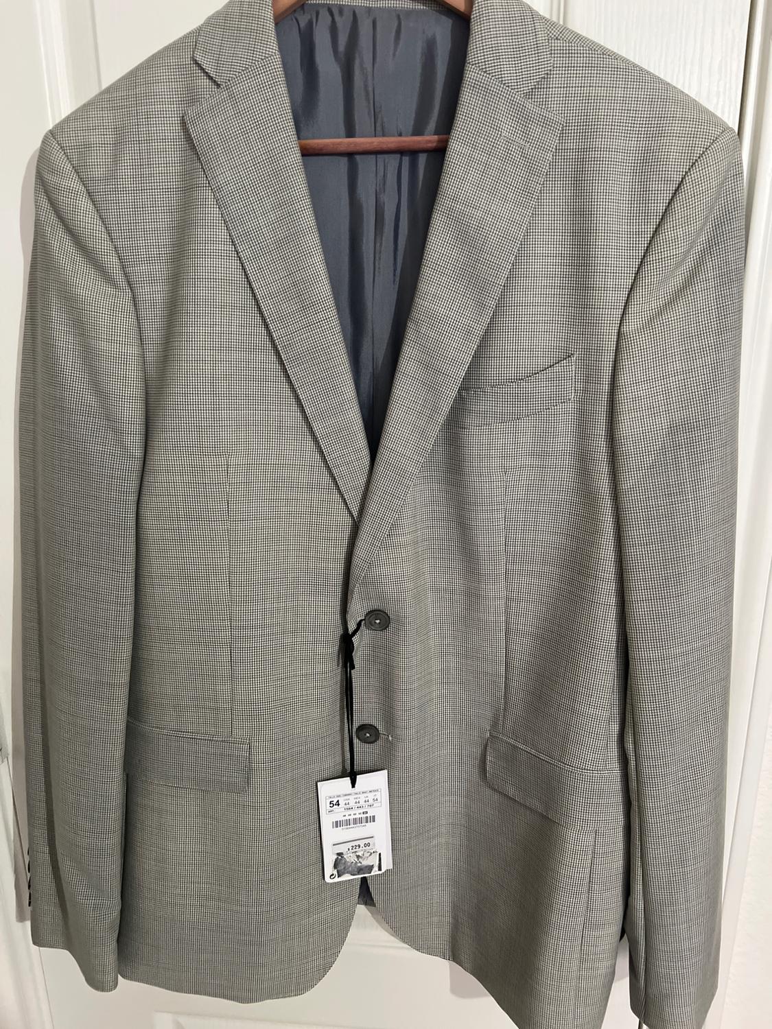Gray jacket with small checks, hanging on a wooden hanger. Visible tag with product details on the front.