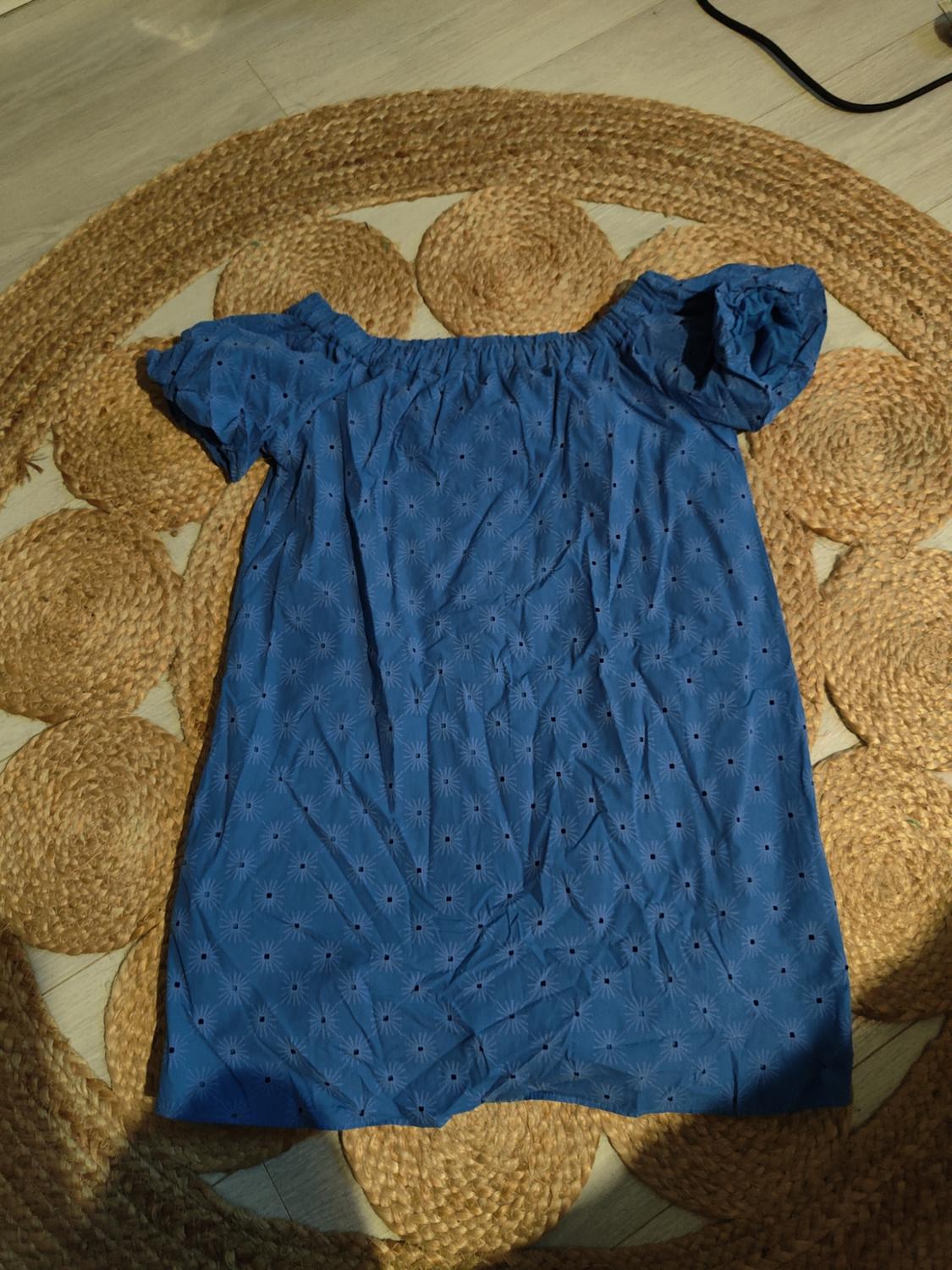 Blue dress with small star print, short puff sleeves, on a jute rug on a light wood floor.