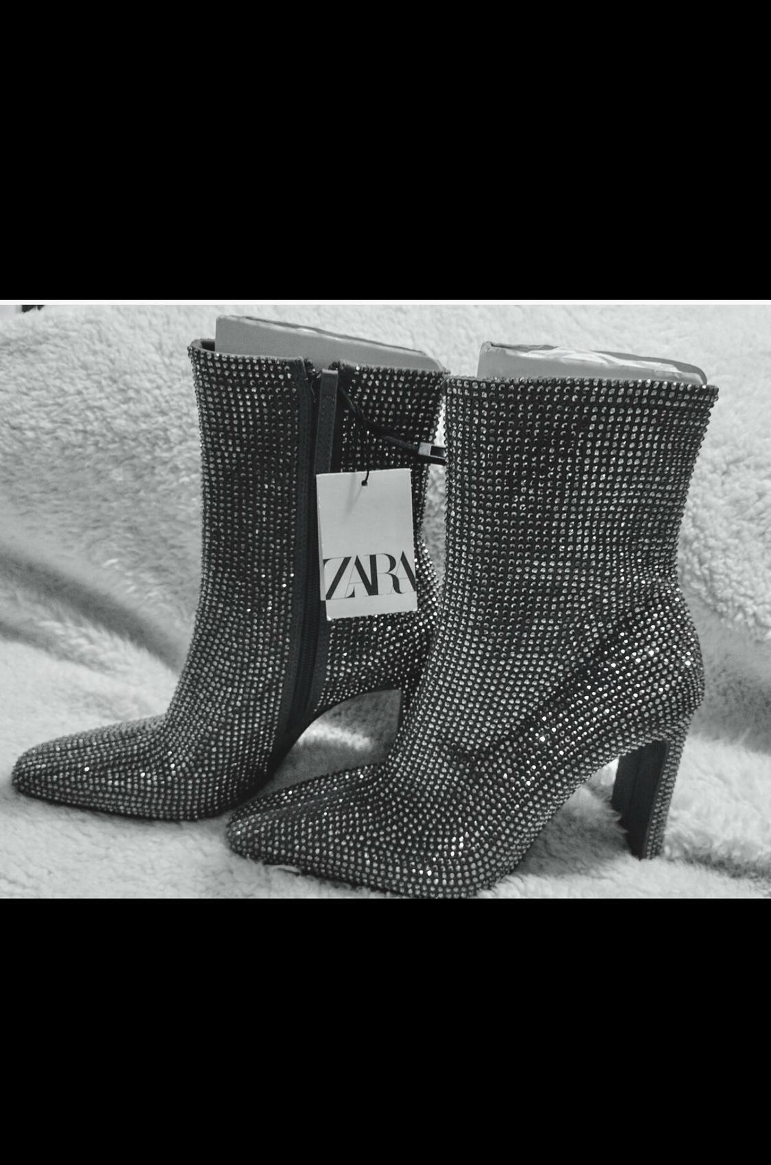 Side view of shiny high-heeled boots with zip fastening and visible label with 'ZARA' text.