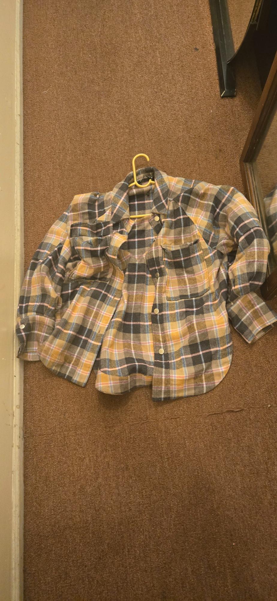 Front view of a checked shirt in brown, yellow, and blue tones with front pockets and buttons.