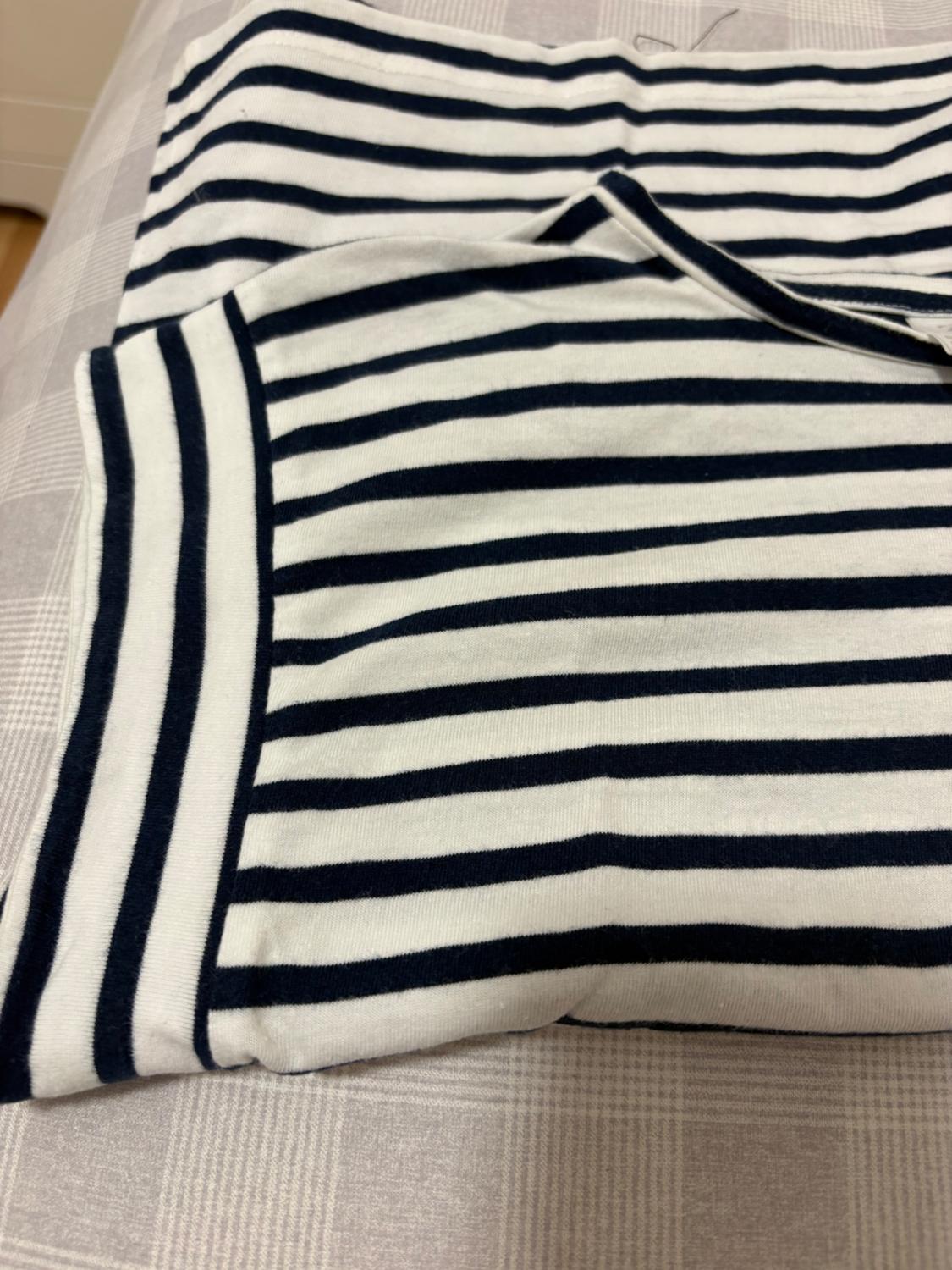 Black and white horizontal striped T-shirt fabric on a grey checked fabric surface.
