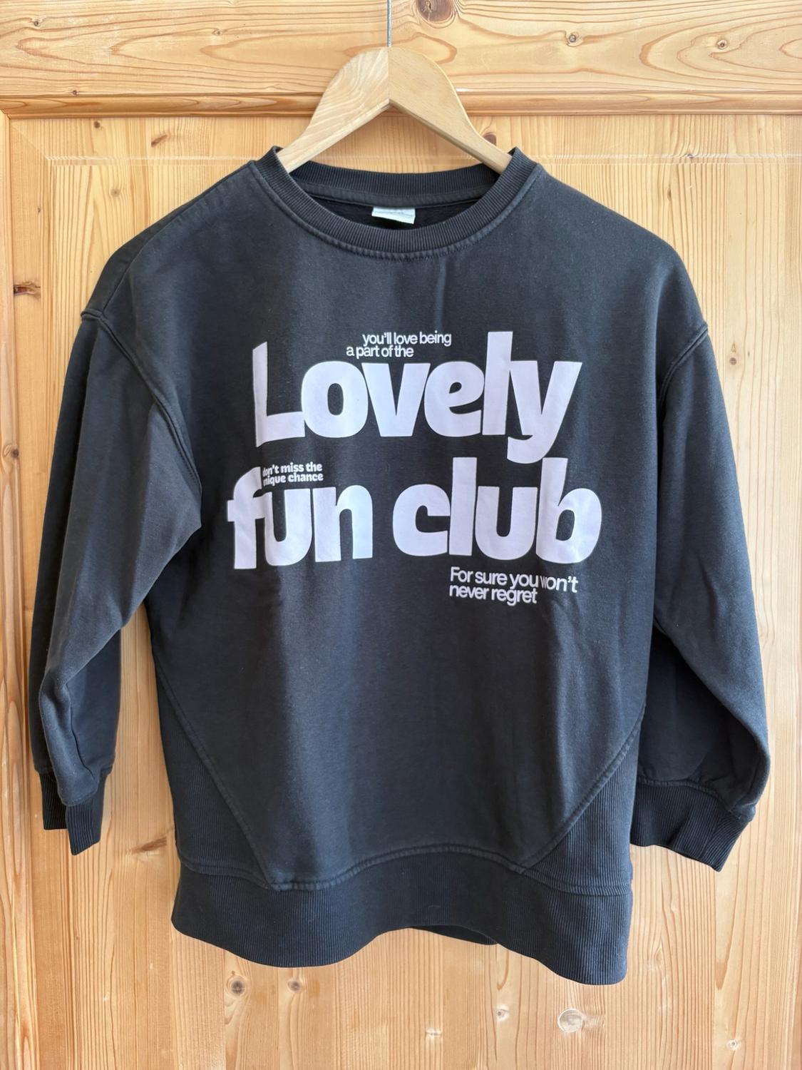 Dark grey sweatshirt on a hanger. Text: you'll love being a part of the Lovely don't miss the unique chance fun club For sure you won't ever regret