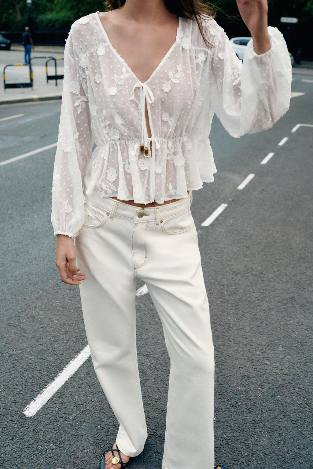 White blouse set with embroidery, V-neck, front ties, and elastic waistband, and white pants with front pockets.