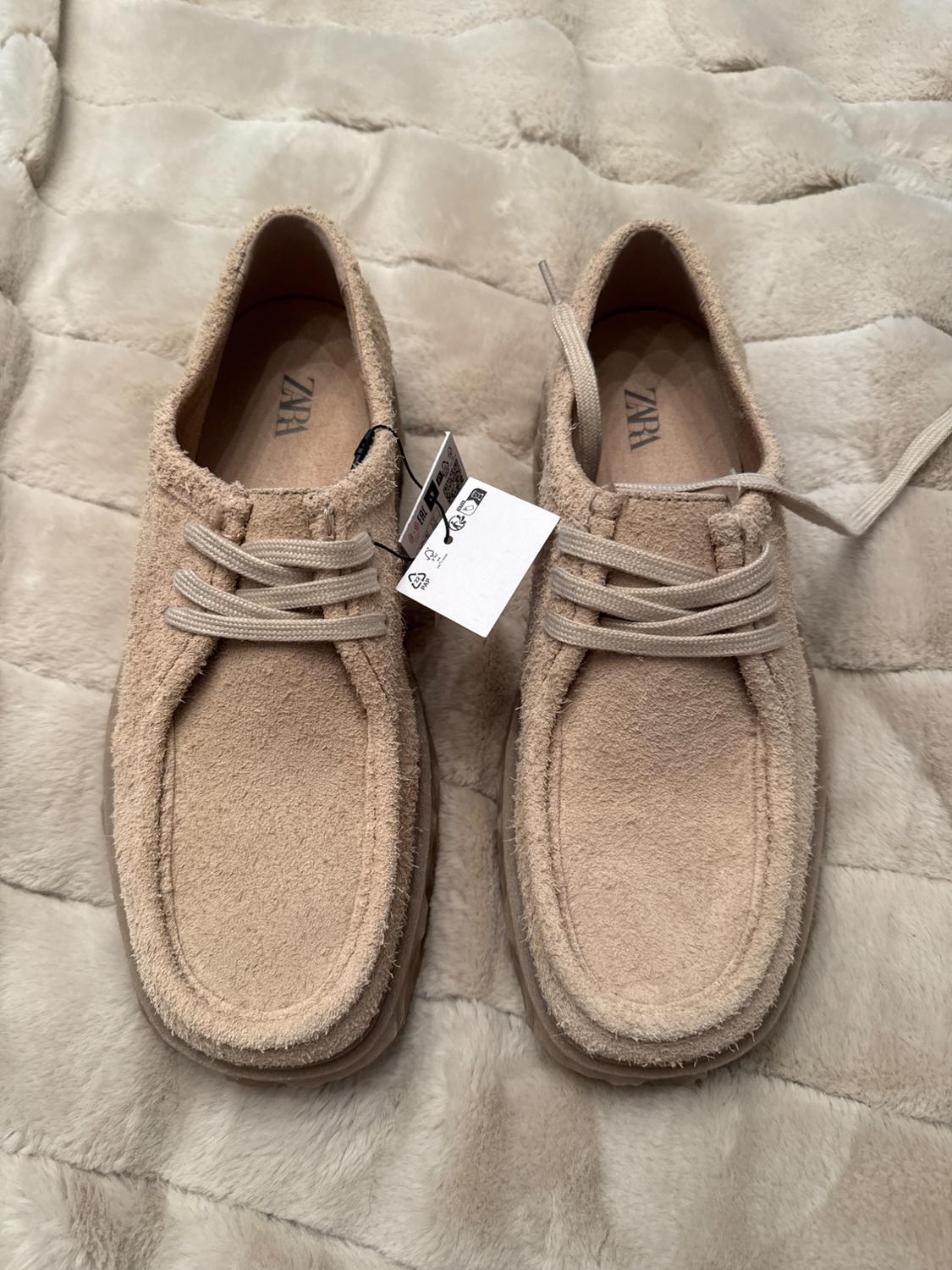 Beige suede lace-up shoes on a padded surface. Visible label with "ZARA" logo inside.