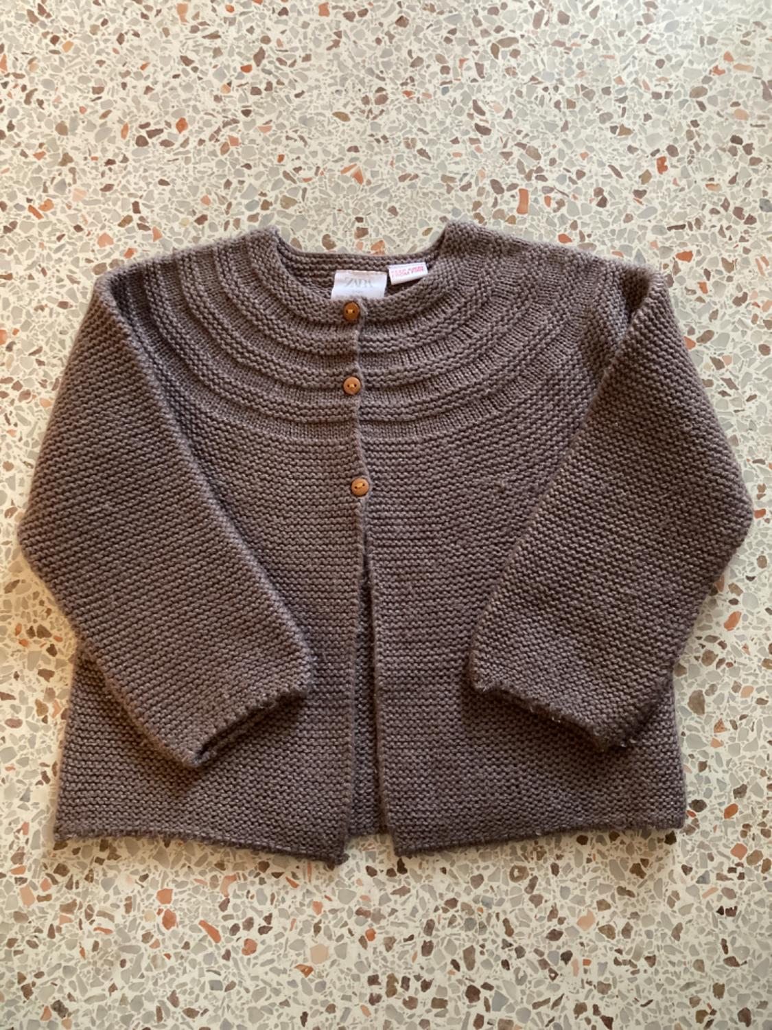 Front view of a brown jacket with wooden buttons and chunky knit fabric.