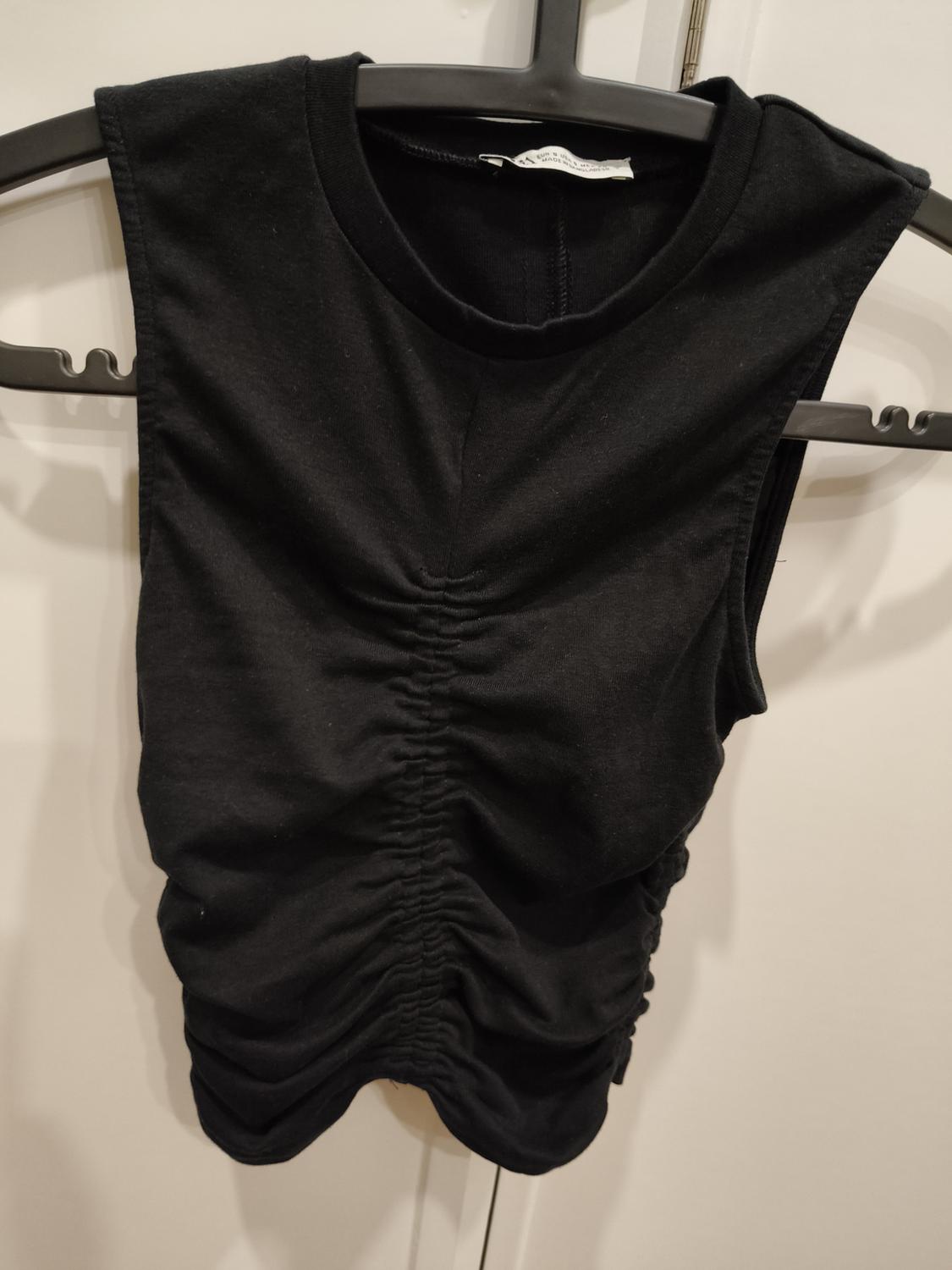 Front view of a black sleeveless t-shirt with central ruching.