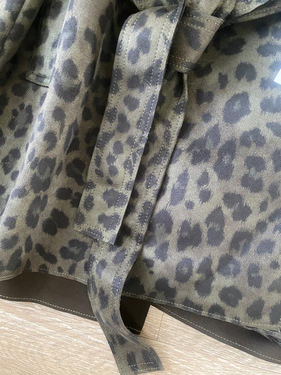 Leopard print fabric in brown and black tones, with visible seams and a knotted belt on a light wooden floor.