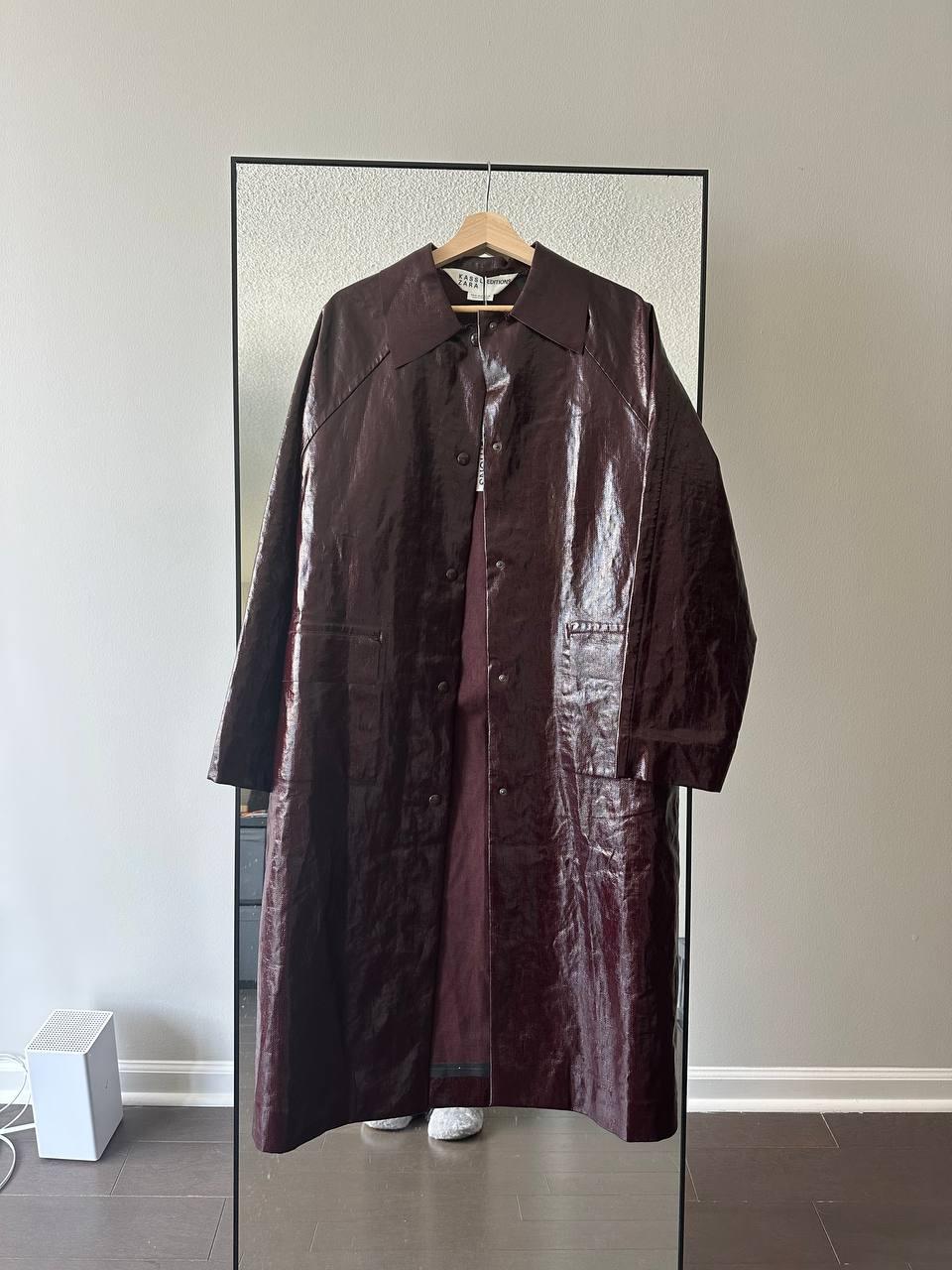 Front view of a dark brown long coat with front buttons and side pockets.