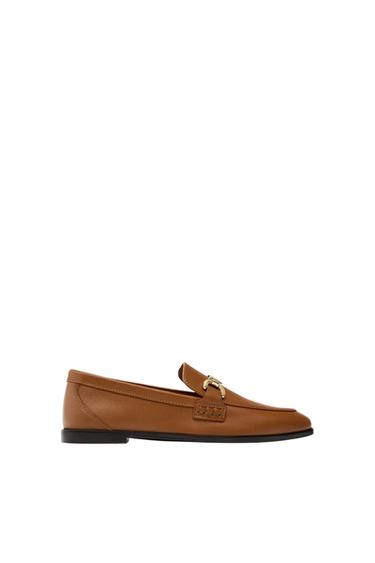 Side view of a brown loafer with gold metal detail.