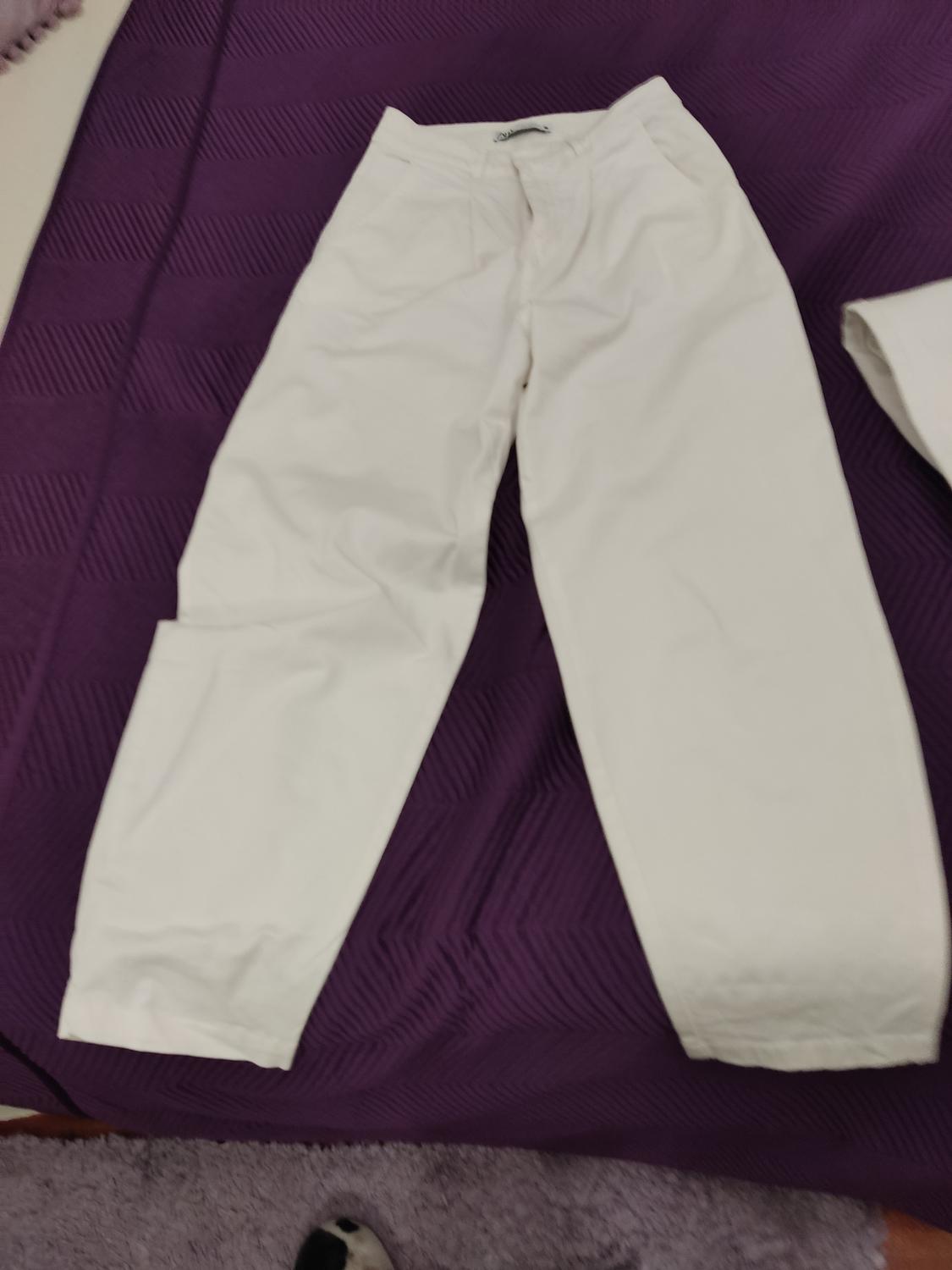 White trousers on a purple quilt with a geometric pattern. Part of a similar garment visible on the right.