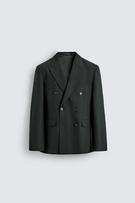 Front view of a dark green double-breasted blazer with peak lapels, flap pockets at the hip and double-breasted fastening.