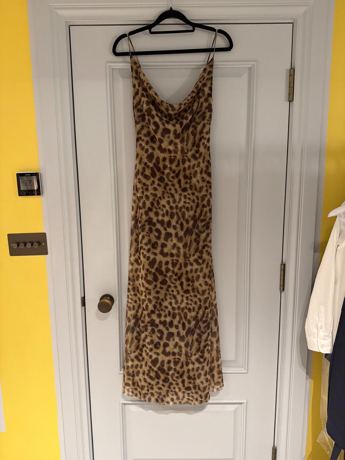 Long leopard print dress hanging on a white door. Yellow background with a thermostat showing 22°C.