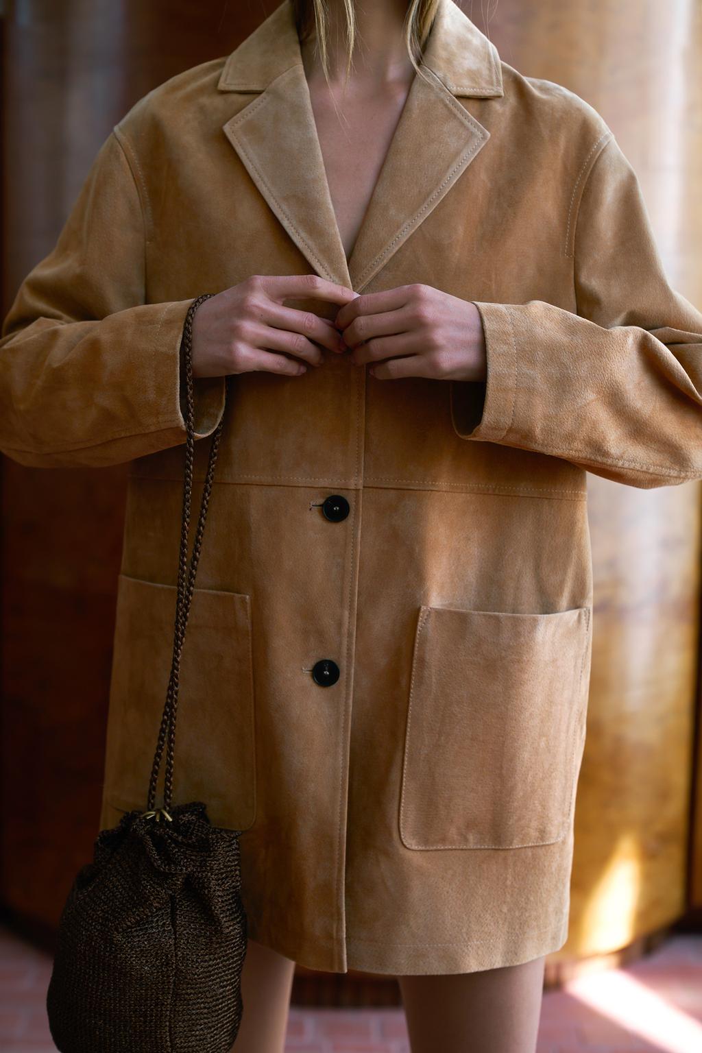 Medium shot of a brown jacket with wide lapels, black buttons, and large front pockets.