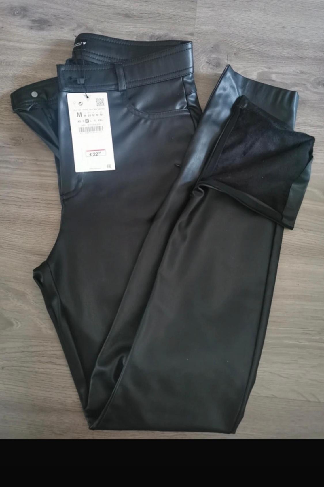 Detail of black trousers with visible label.