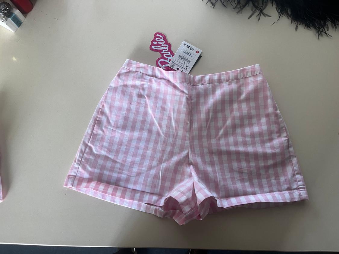 Pink and white checked shorts on a white table. Visible label with the text "Barbie" in pink.