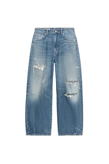 Front view of baggy indigo jeans with rips, mid-rise, five pockets, and front zip and button closure.