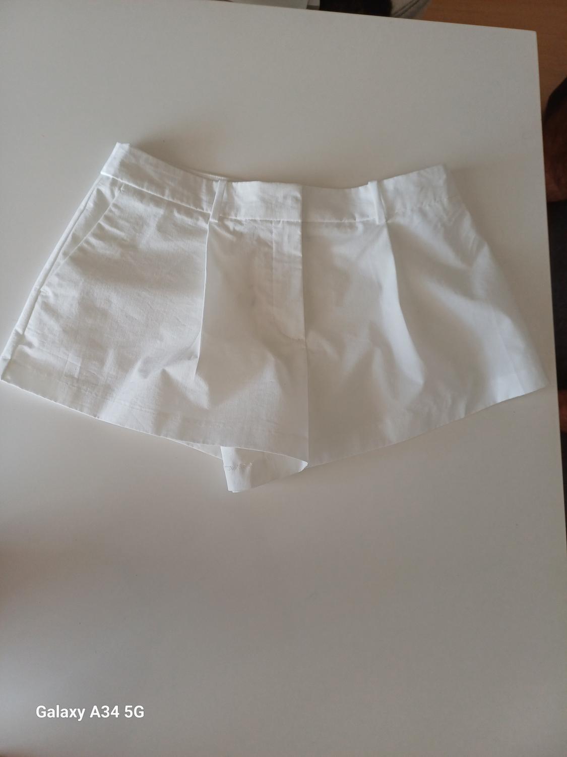 White shorts on a white surface. Text in the bottom left corner: "Galaxy A34 5G".