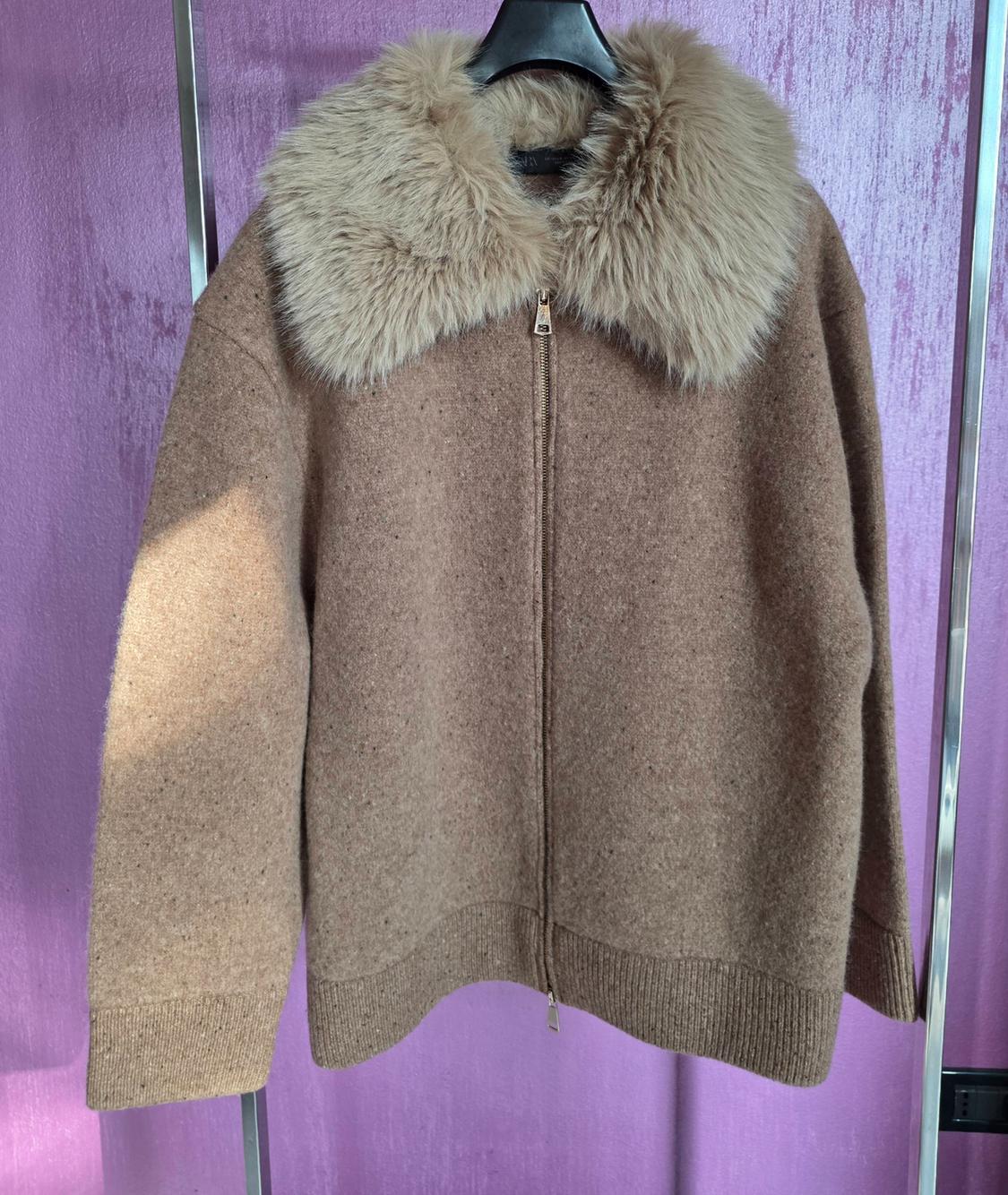 Brown jacket with zip and faux fur collar, hanging on a black hanger against a purple background.