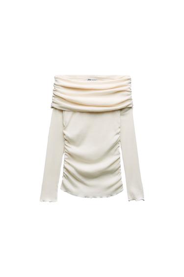 Front view of a white blouse with a draped neckline and long sleeves.