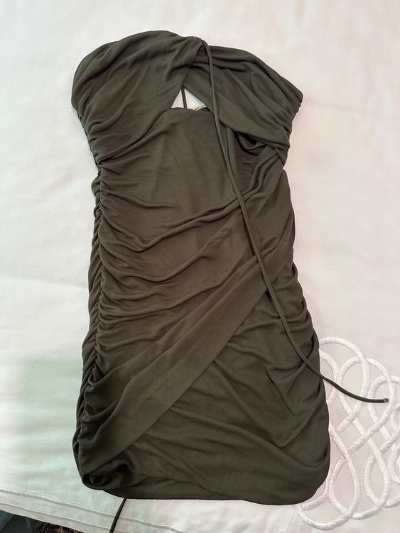 Olive green draped dress on a white surface, with a strapless design and delicate lace-up detail.