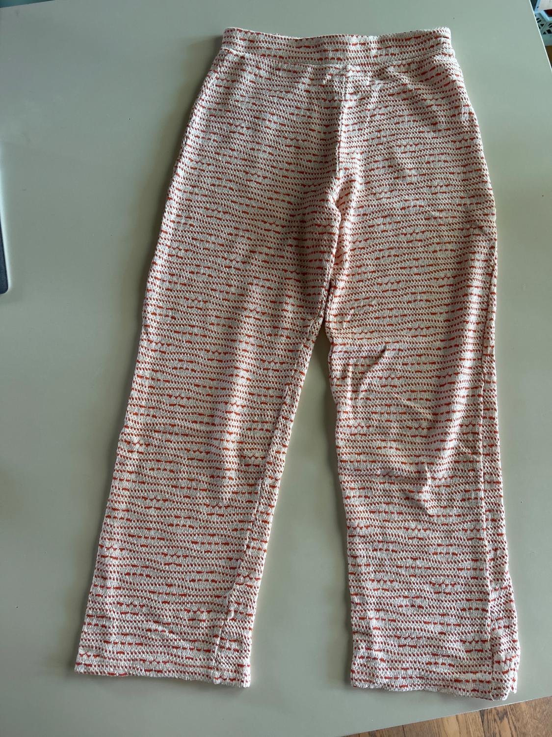 Front view of red and white patterned trousers, elasticated waistband.