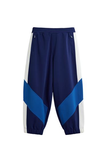 Front view of blue trousers with white and blue stripes, side pockets and elasticated waistband.