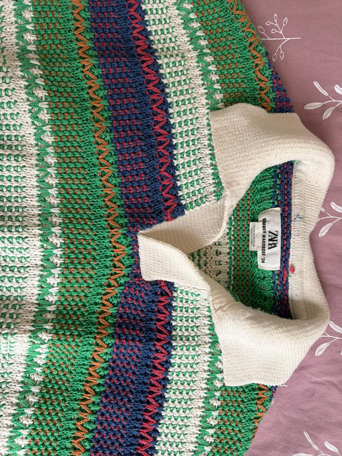 Green, white, and blue striped knit polo shirt on a pink background. Neck label with the text "ZARA SUMMER WARDROBE '24".