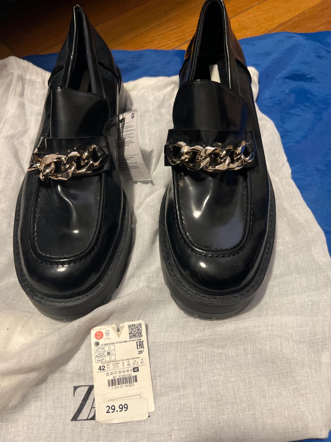 Black shoes with a metal chain on the vamp, visible tag with a price of £29.99.