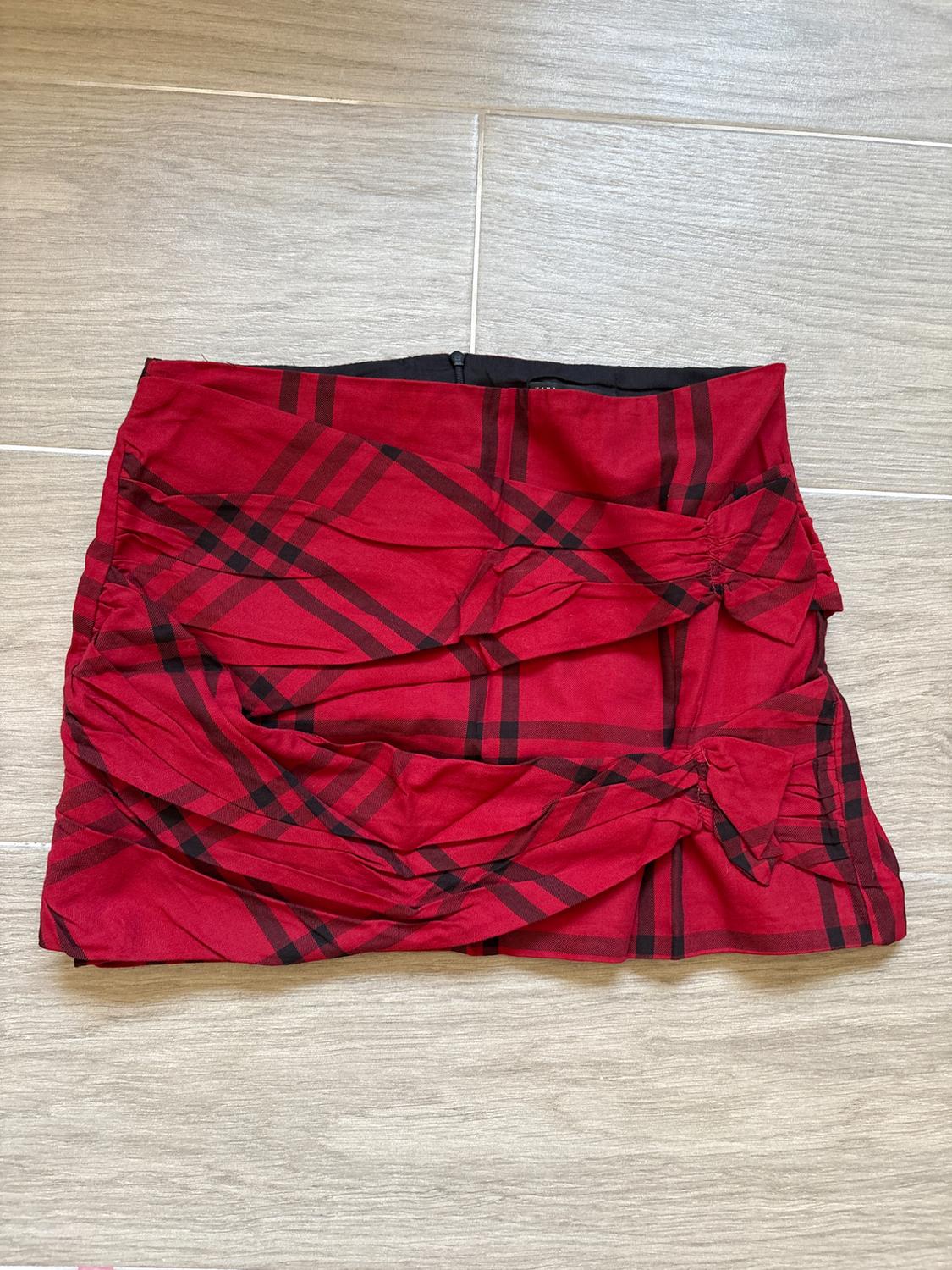 Front view of a red skirt with a black checked pattern and decorative ruffles.