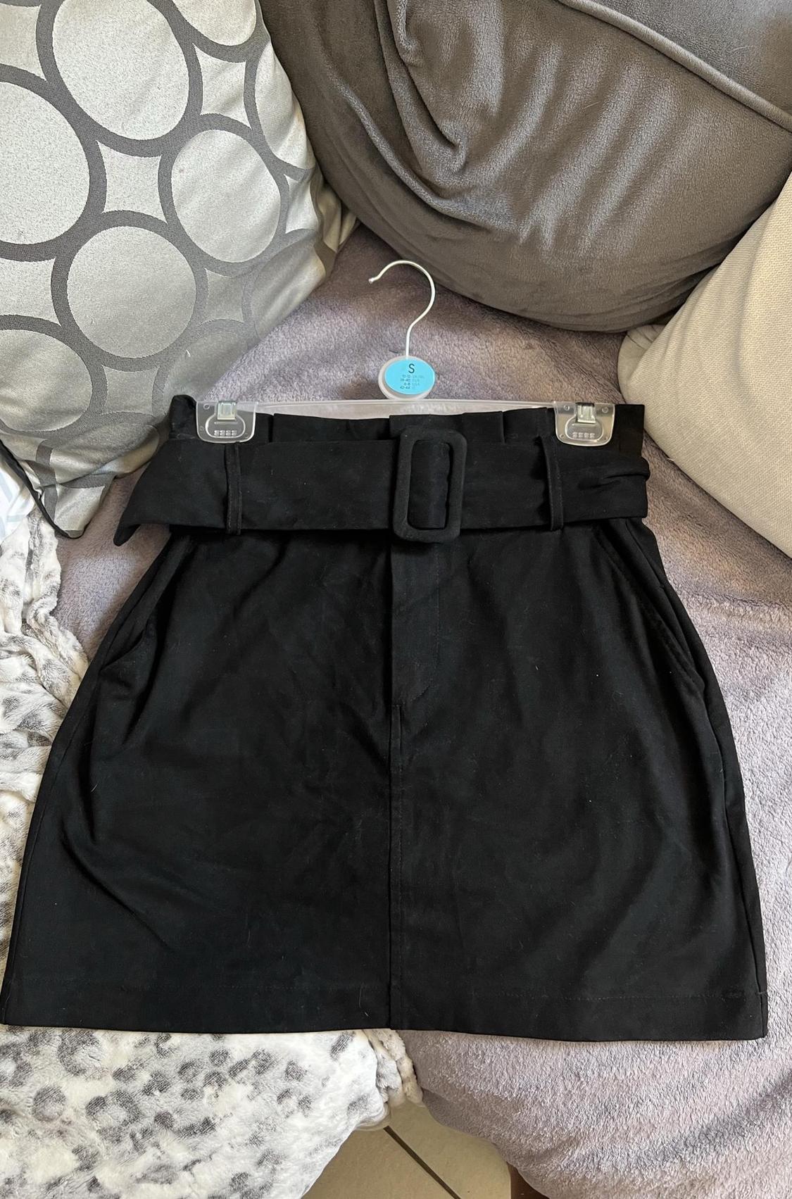 Front view of a black skirt with a belt and side pockets.