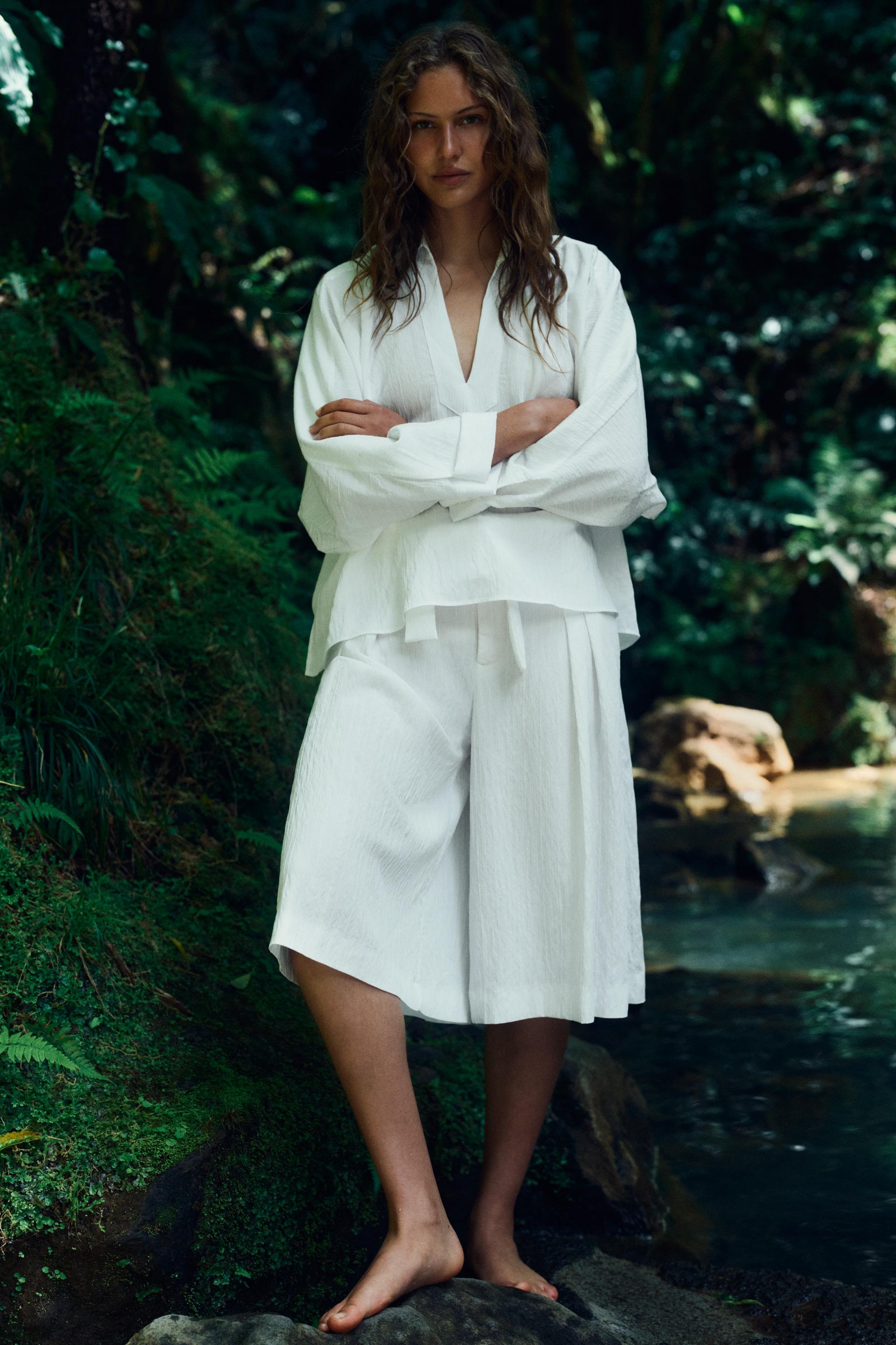 Conjunto de blusa blanca holgada con cuello en pico y pantalón corto ancho de lino.