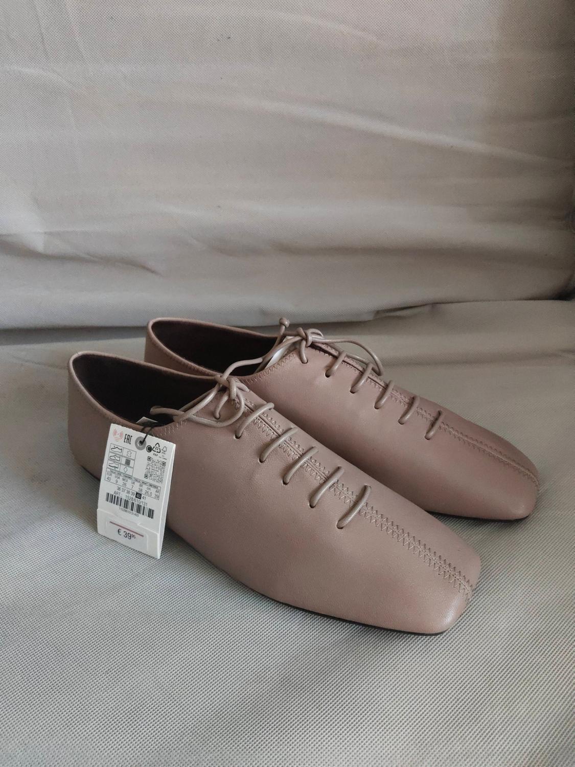 Beige leather lace-up shoes on a grey background. Visible tag with a price of €39.