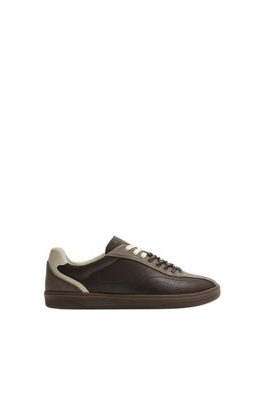Side view of a brown athletic shoe. Design with combined panels, double lacing, flat sole, and light detail on the heel.