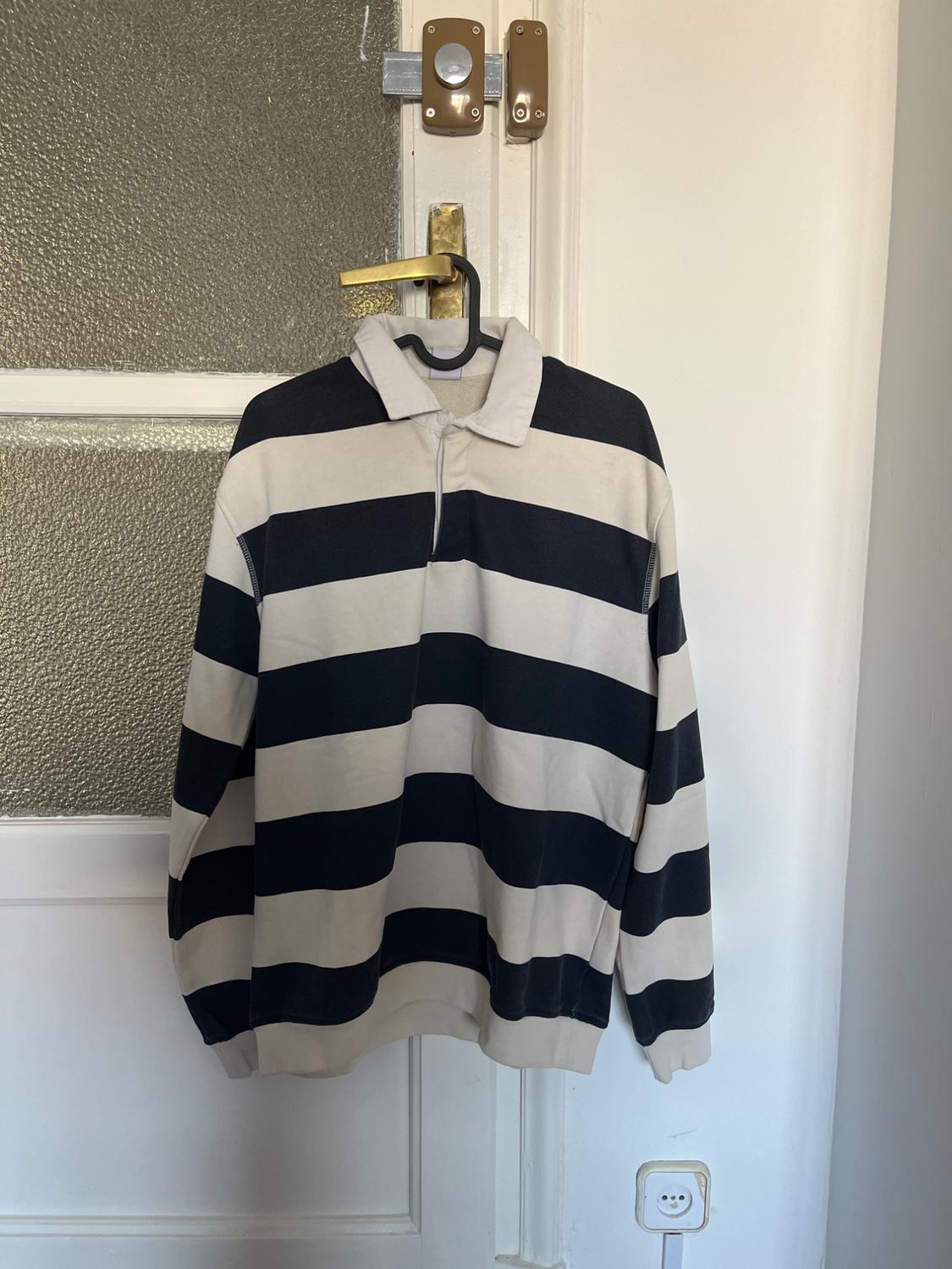 Front view of a black and beige wide-striped polo neck jumper.