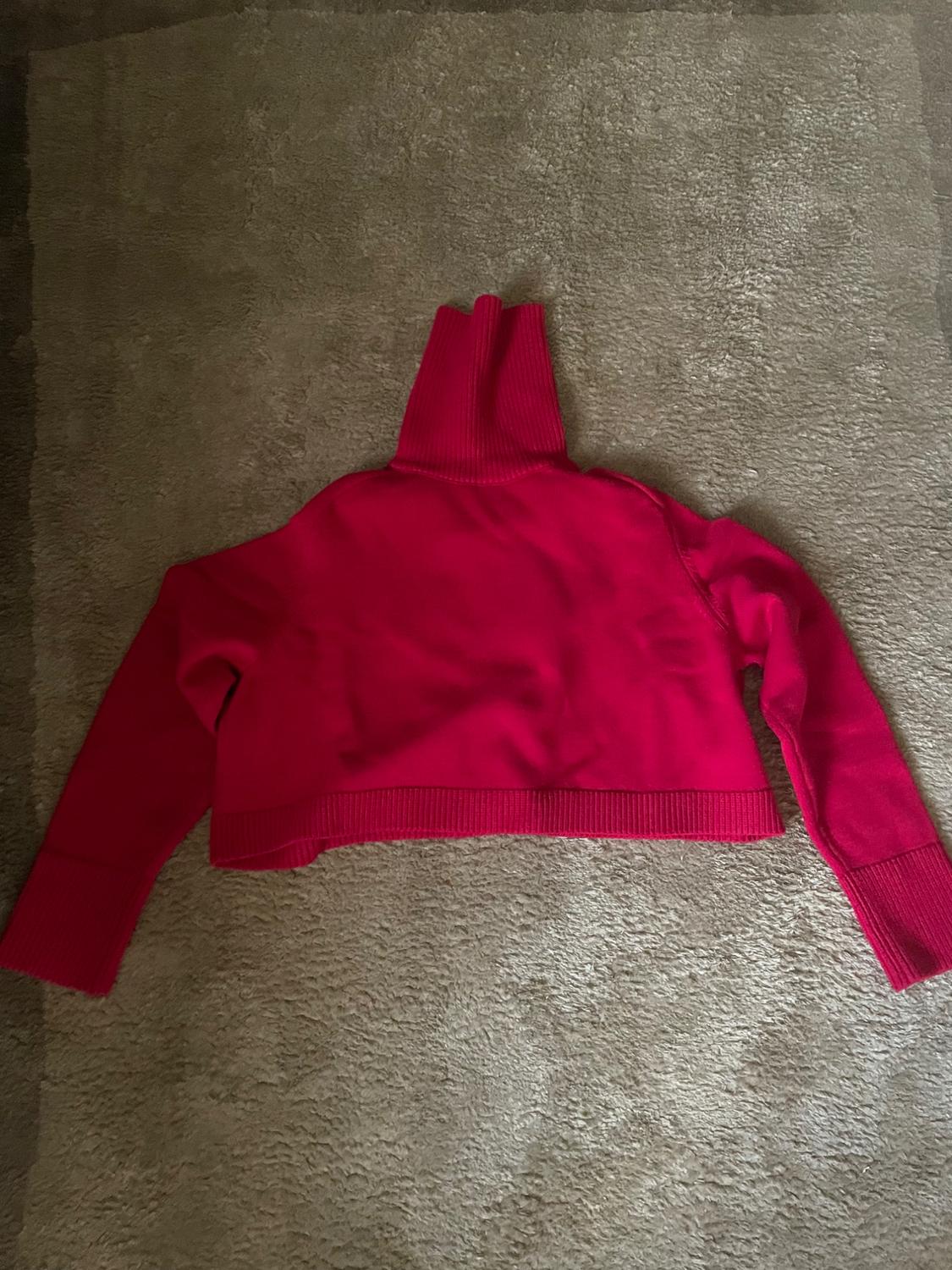 Rear view of a red jumper with a high neck and long sleeves.
