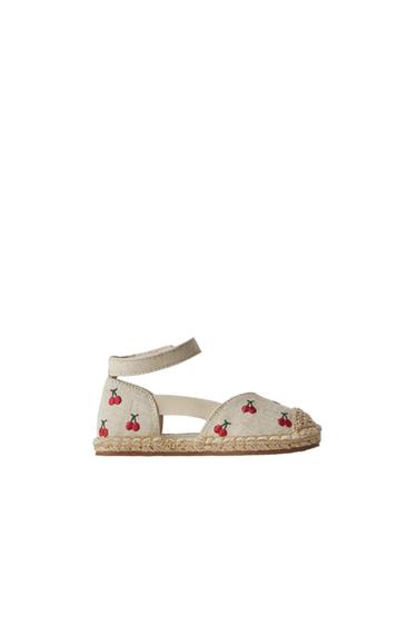 Side view of an espadrille with a cherry print and esparto sole.