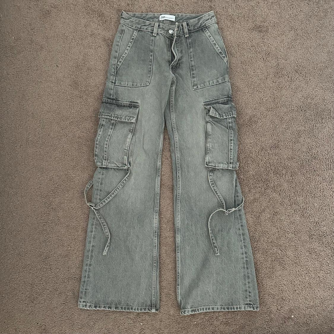 Front view of gray pants with cargo pockets and side straps.