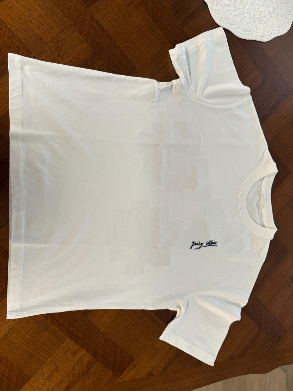 Λευκό κονtomάνικο t-shirt απλωμένο σε ξύλινο πάτωμα. Έχει το κείμενο "Juicy Vibes" στο στήθος.