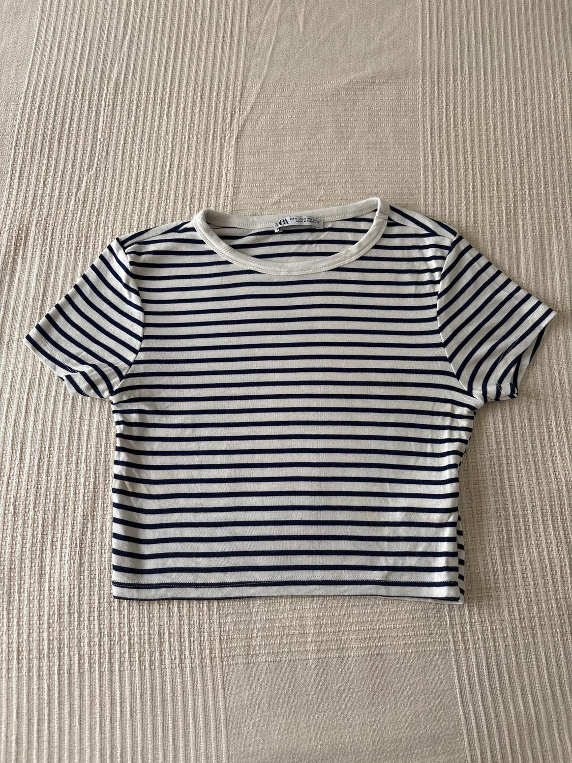 Navy and white horizontal striped T-shirt on a textured beige surface.