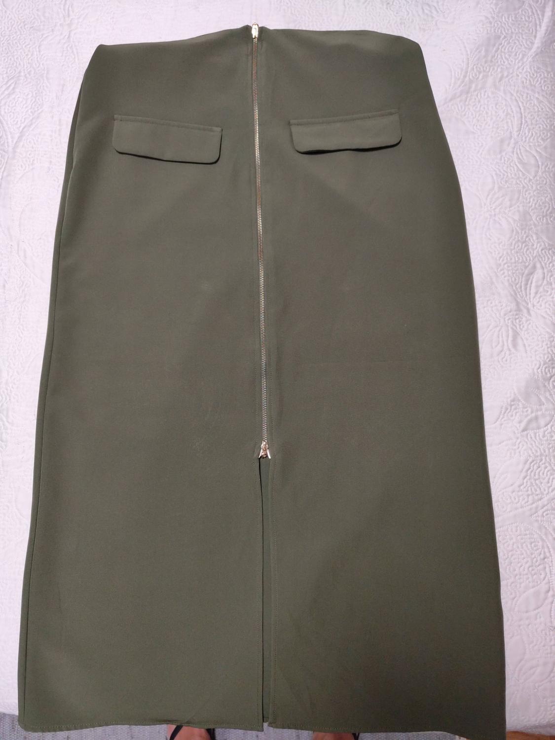 Olive green midi skirt laid out on a textured white background. It features a front zip and two flap pockets.