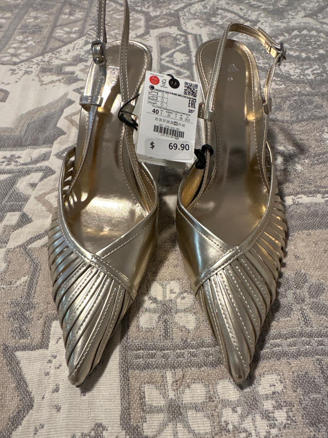 Gold high-heeled shoes with a braided design and a price tag of $69.90 on a geometric patterned surface.