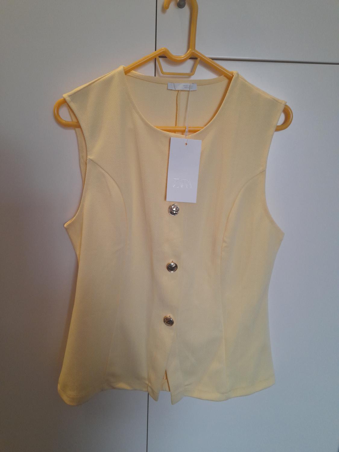 Light yellow sleeveless waistcoat with silver buttons, hanging on a yellow hanger. White label visible.